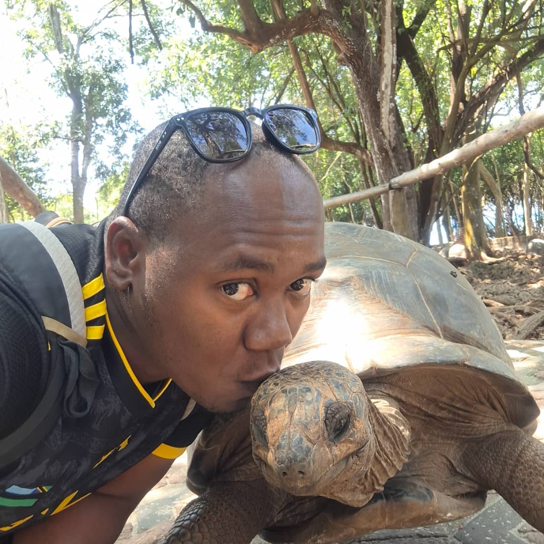 Abdalla kissing a giant tortoise on Prison Island